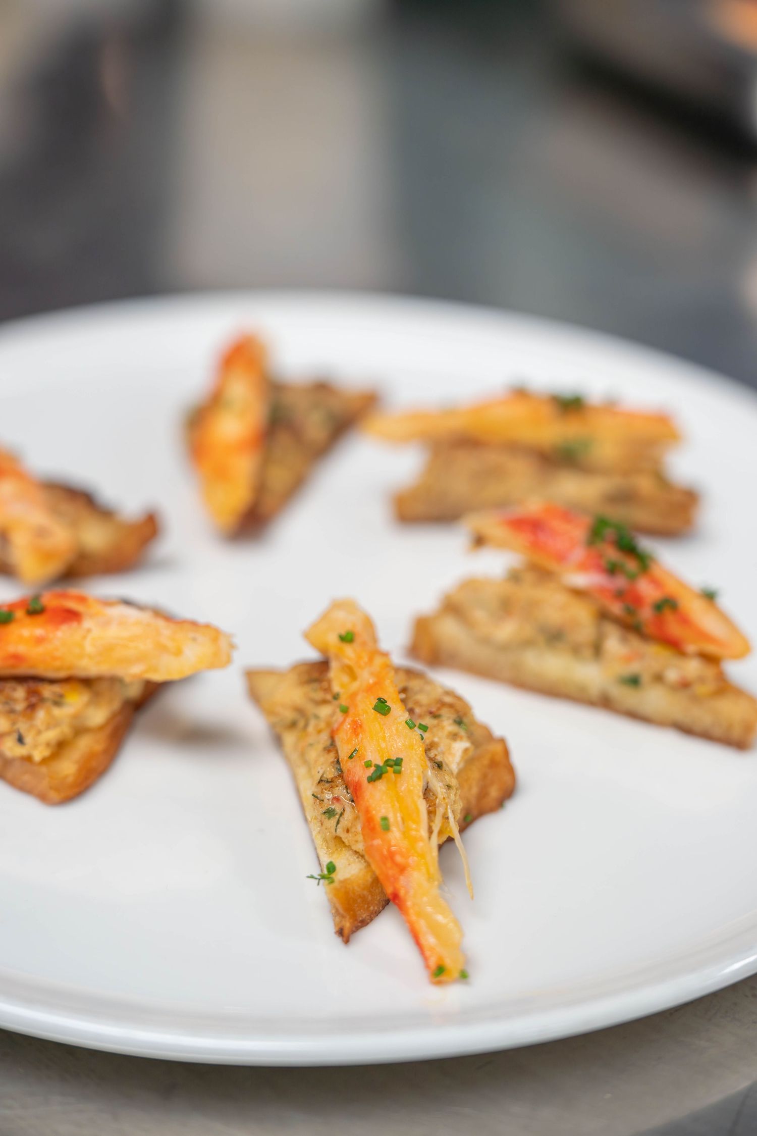 Small appetizer bites with shrimp and herbs served on a white plate with garnish. Food product photography Quad Cities.