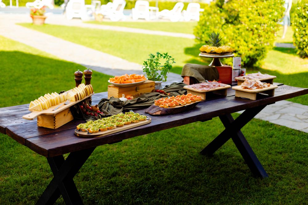 Long wooden tables set up outdoors with appetizers and catering displays.
