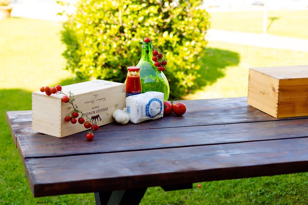 Drinks and wooden boxes arranged on a dark wood table outdoors in natural sunlight.