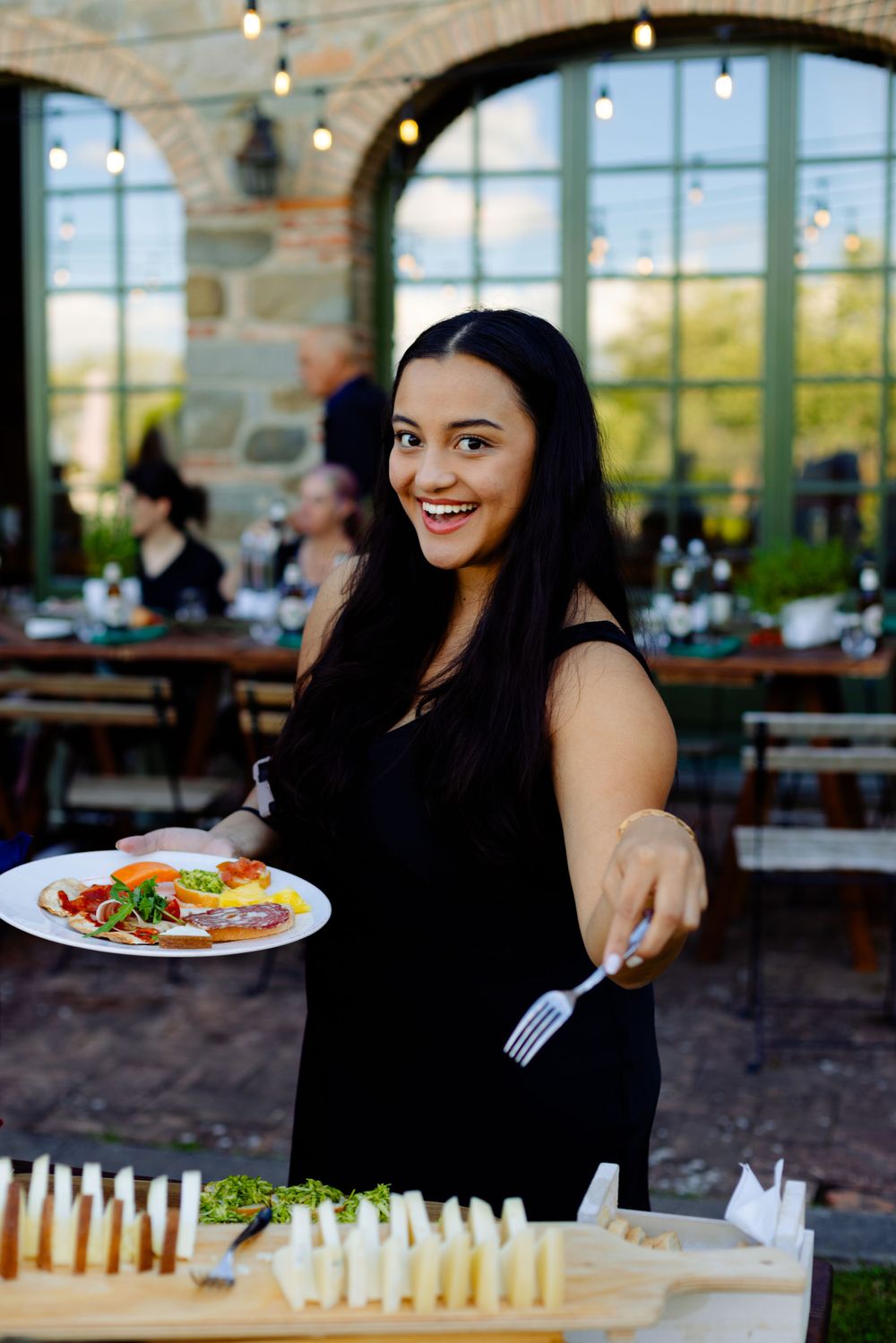Person serving food at outdoor dining event with appetizer display.
