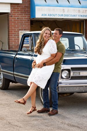 Romantic moment captured near vintage cars with a white eyelet dress and casual denim.
