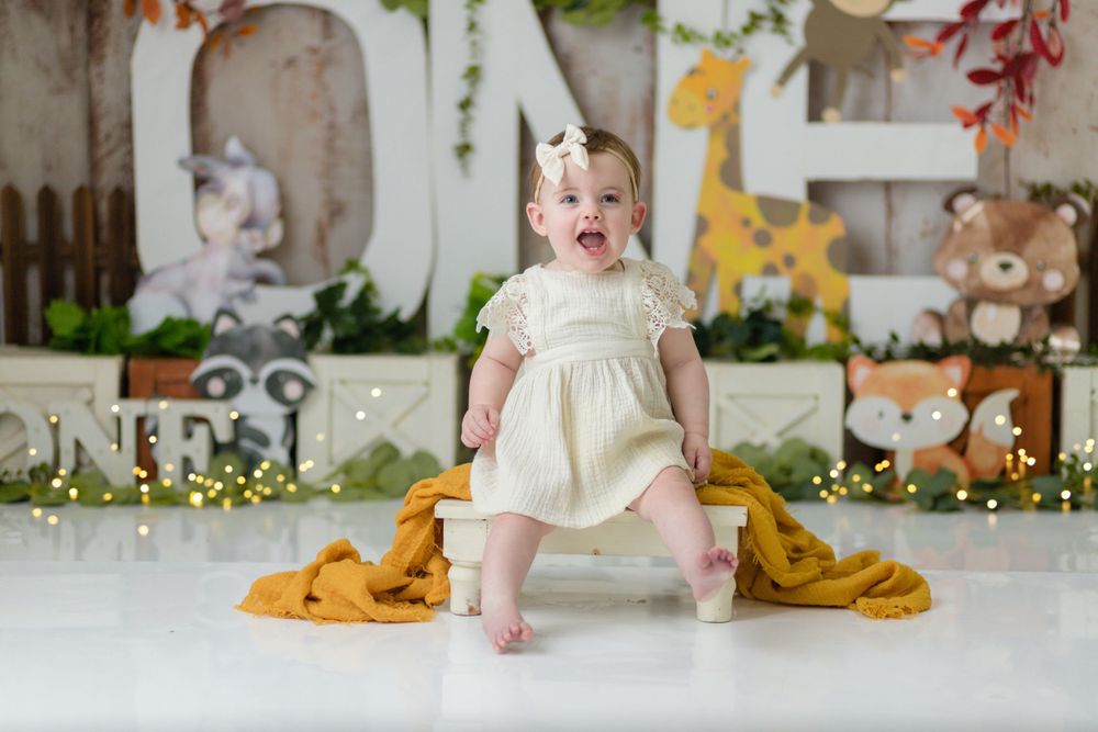 Safari themed set with cream dress, mustard blanket and woodland animal decorations.