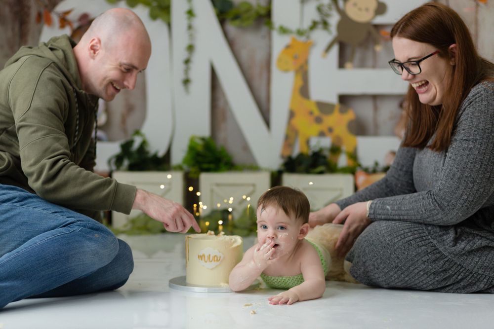 Family gathered around a small cake during a festive photo session with woodland decorations.