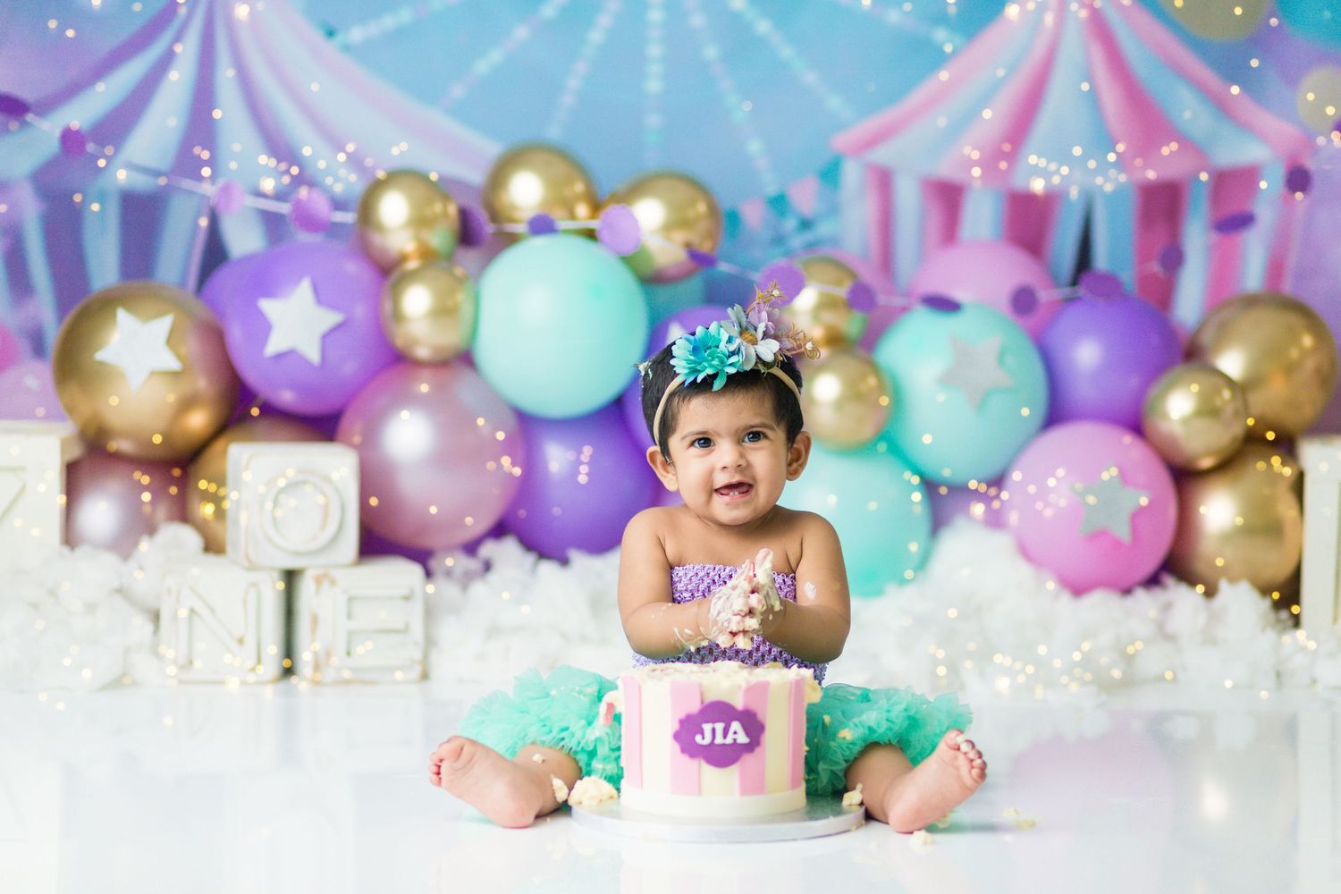 Carnival themed cake smash setup with purple and gold balloons and circus tent decorations.