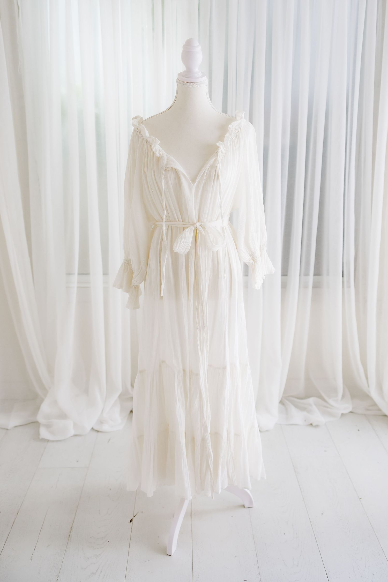 Ethereal white cotton dress with tie waist and tiered skirt on mannequin.