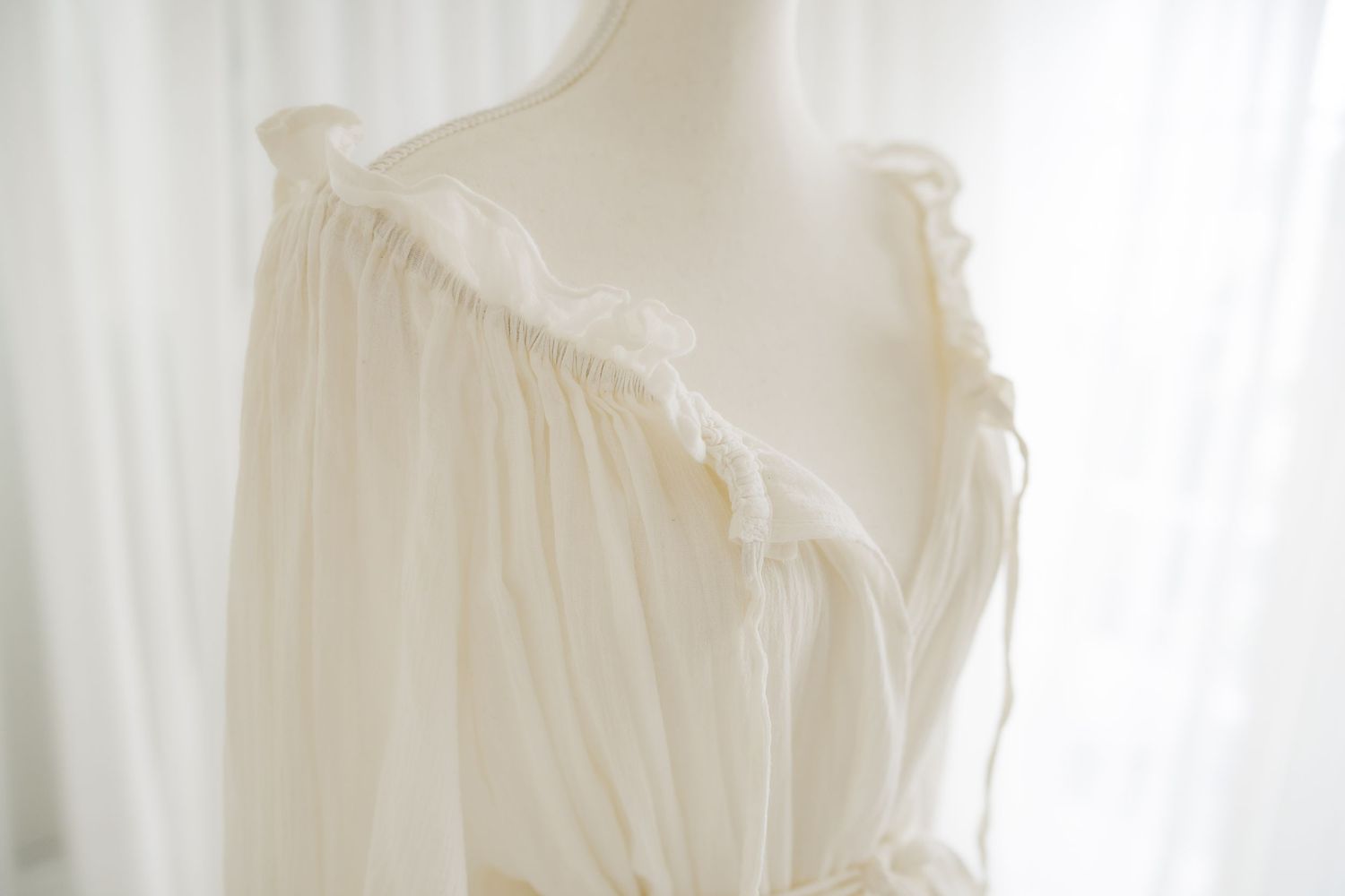 Close-up of white cotton dress showing ruffled neckline detail.