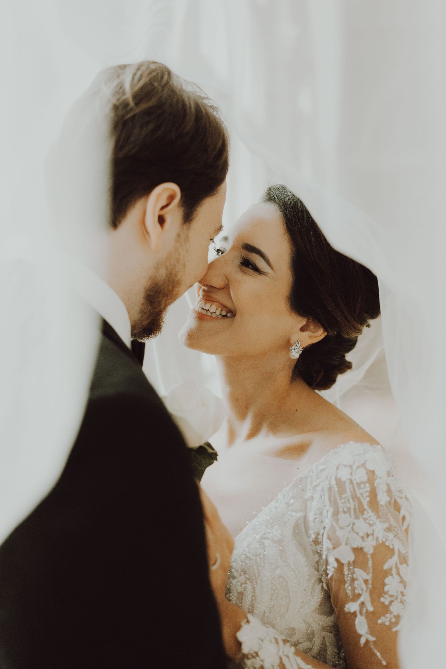 Intimate portrait of a bride and groom sharing a tender moment in soft lighting.