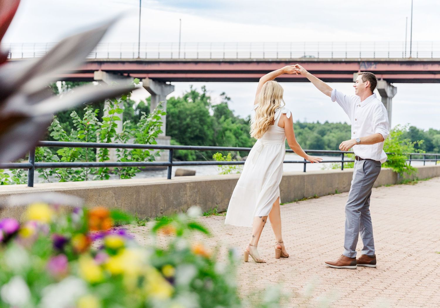 A couple dances together on an outdoor terrace with flowers in the foreground.