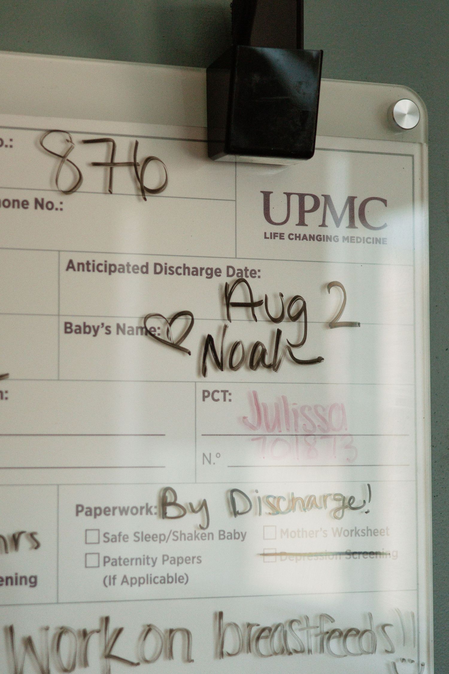 Hospital whiteboard showing discharge information and baby's name with heart doodle.