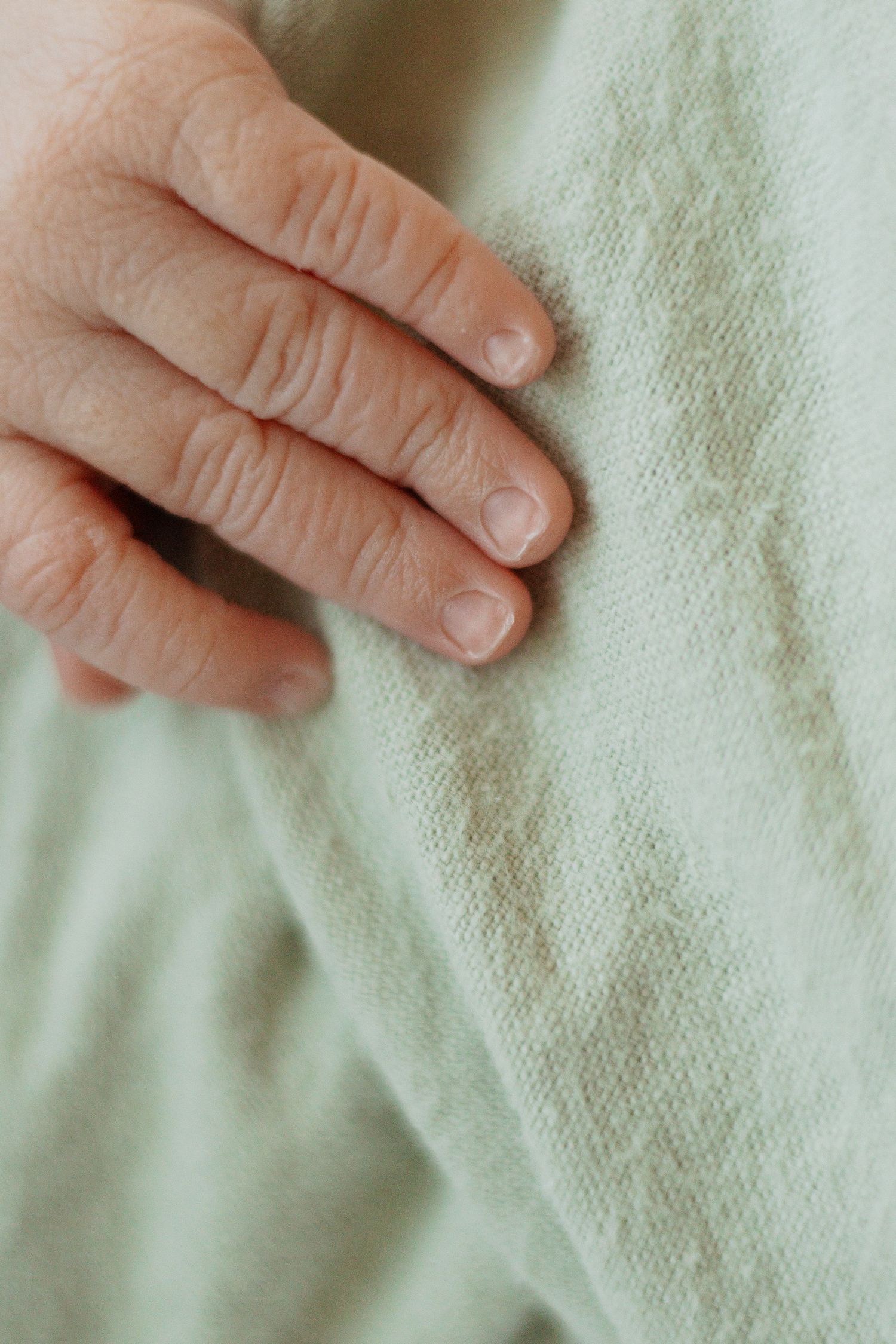 Close-up macro shot of small fingers against soft fabric texture.