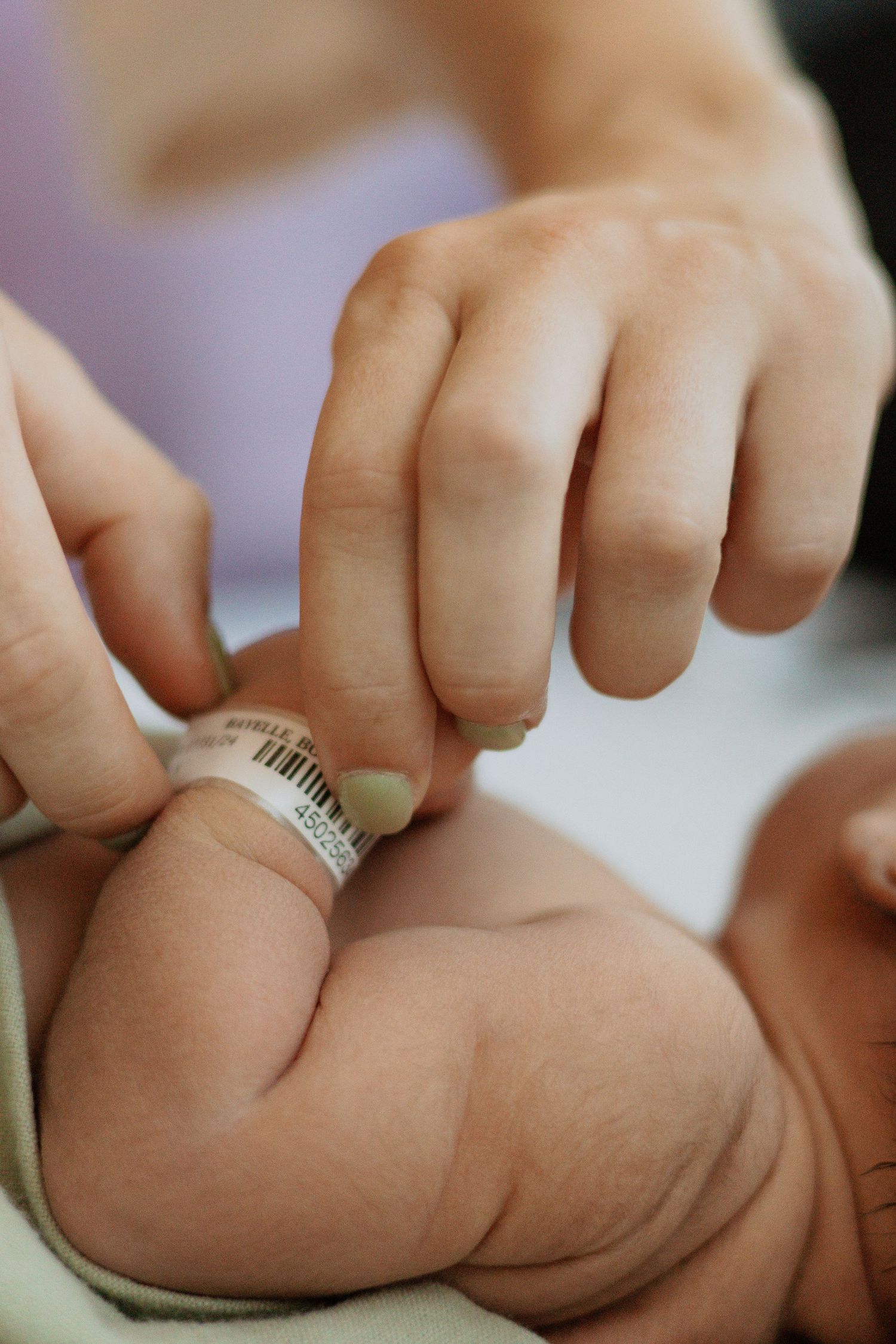 Hospital identification bracelet being placed on newborn baby's wrist.