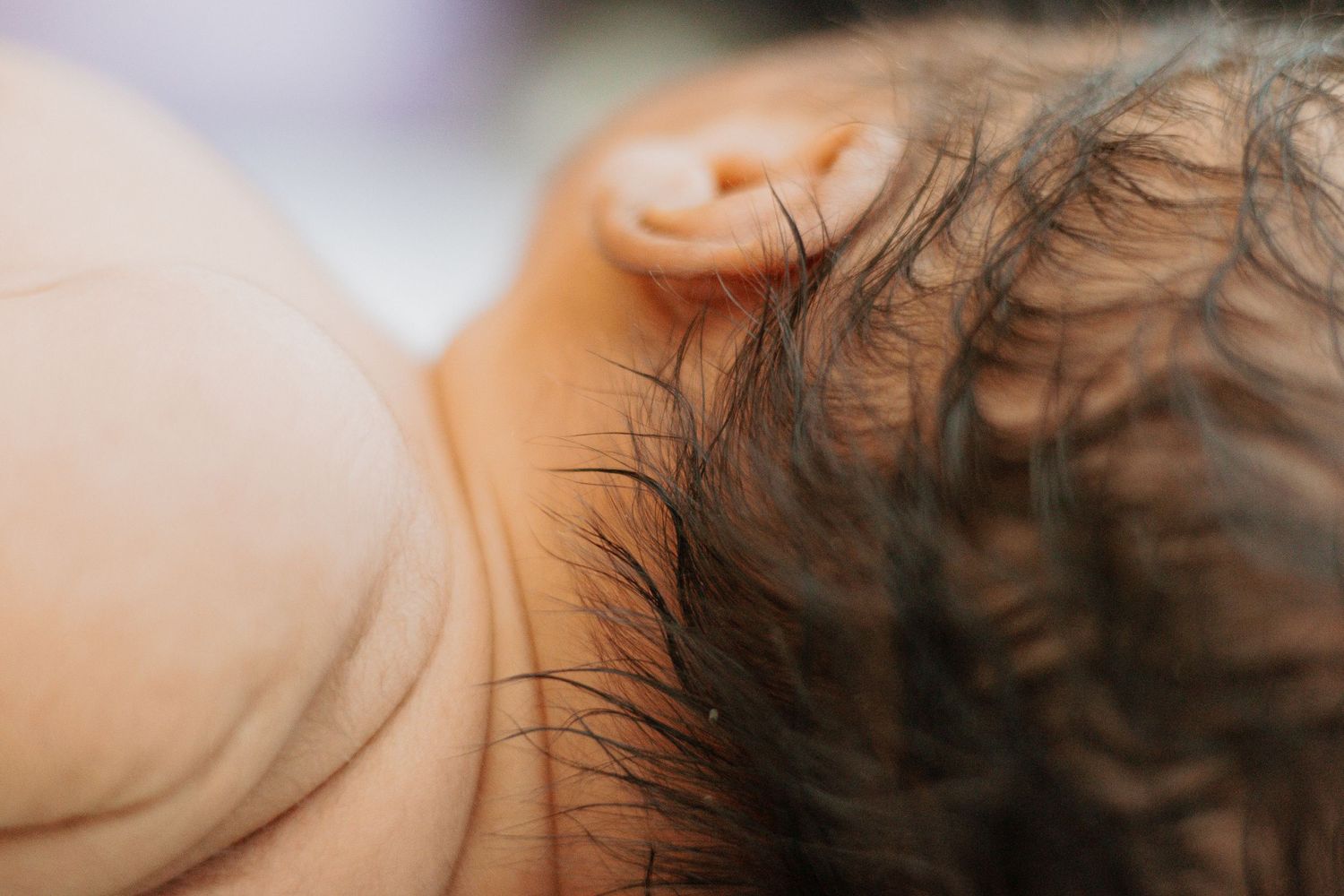 Detail shot of dark newborn hair against soft skin.