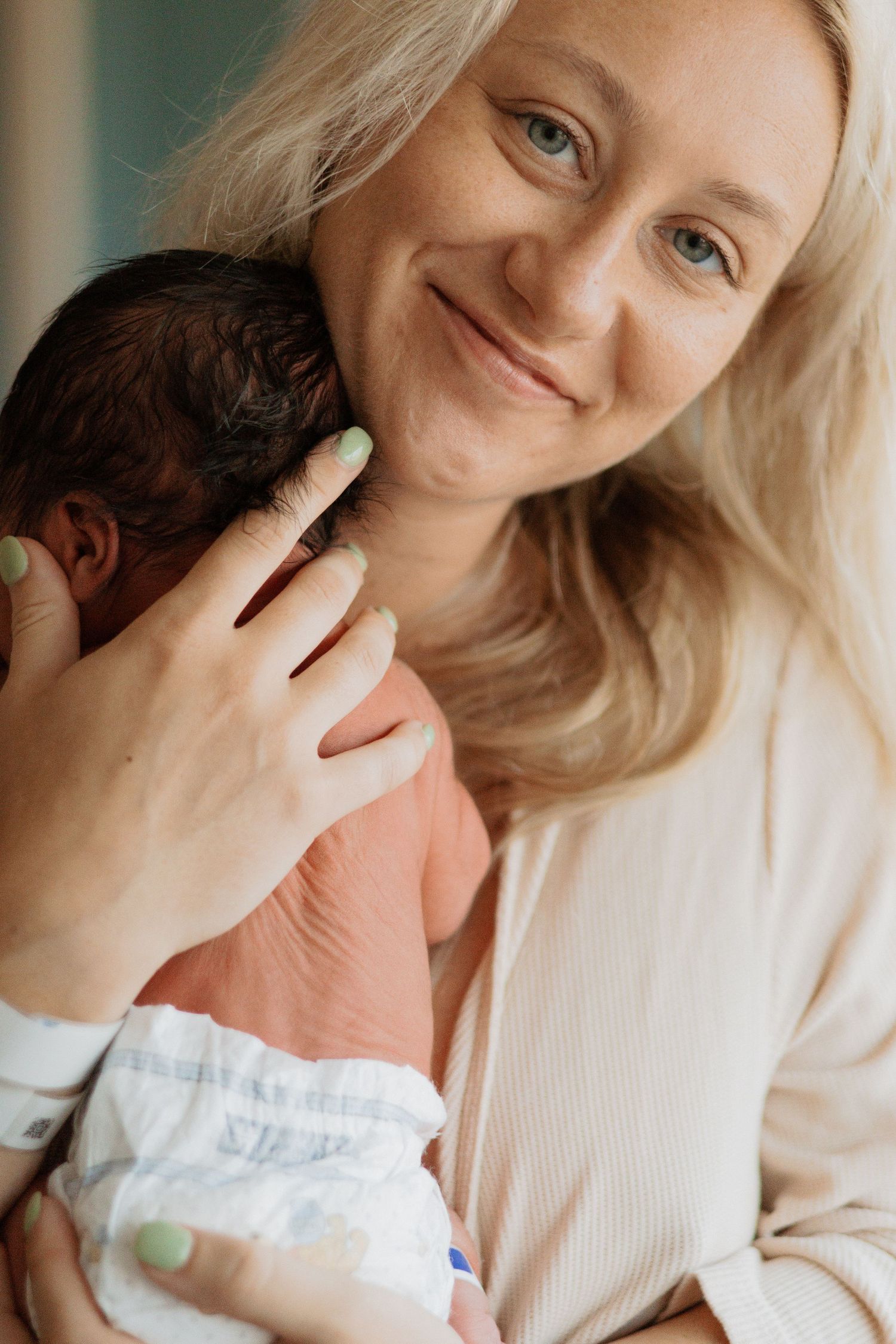 Intimate portrait of parent holding newborn baby in gentle embrace.