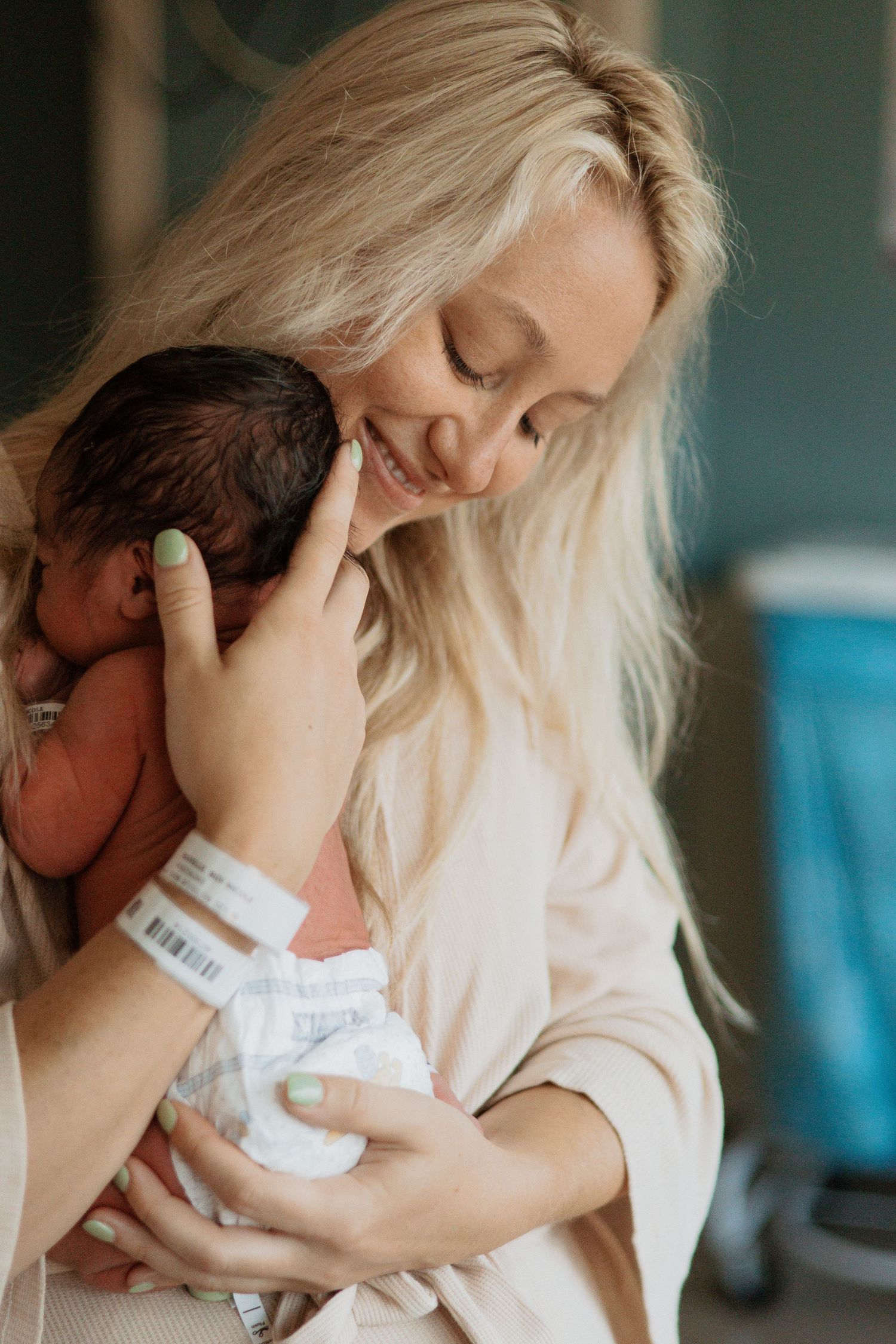 A tender moment between parent and newborn baby in hospital, with gentle embrace and soft lighting.