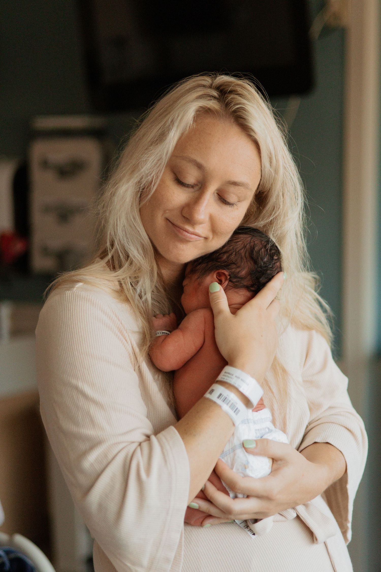 Intimate bonding moment with newborn baby in cozy hospital setting.