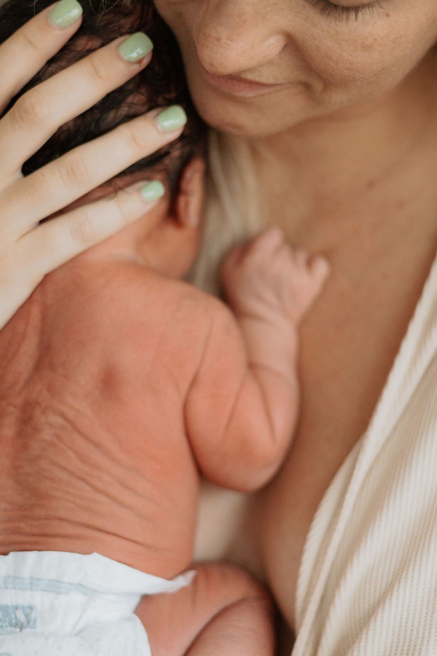 Close-up view of gentle hand caressing newborn baby's head.