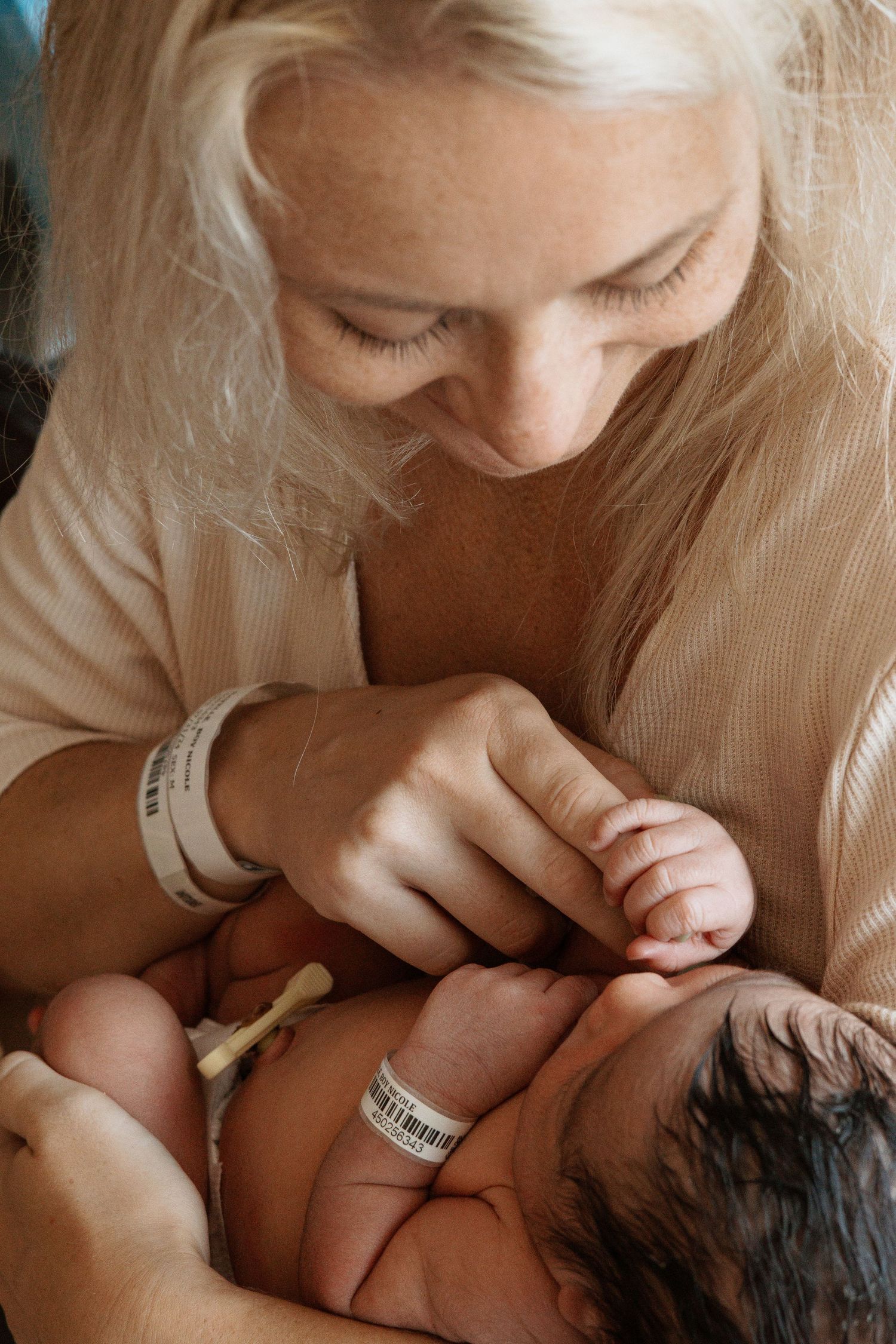 Parent gently touching newborn baby's tiny toes in hospital.