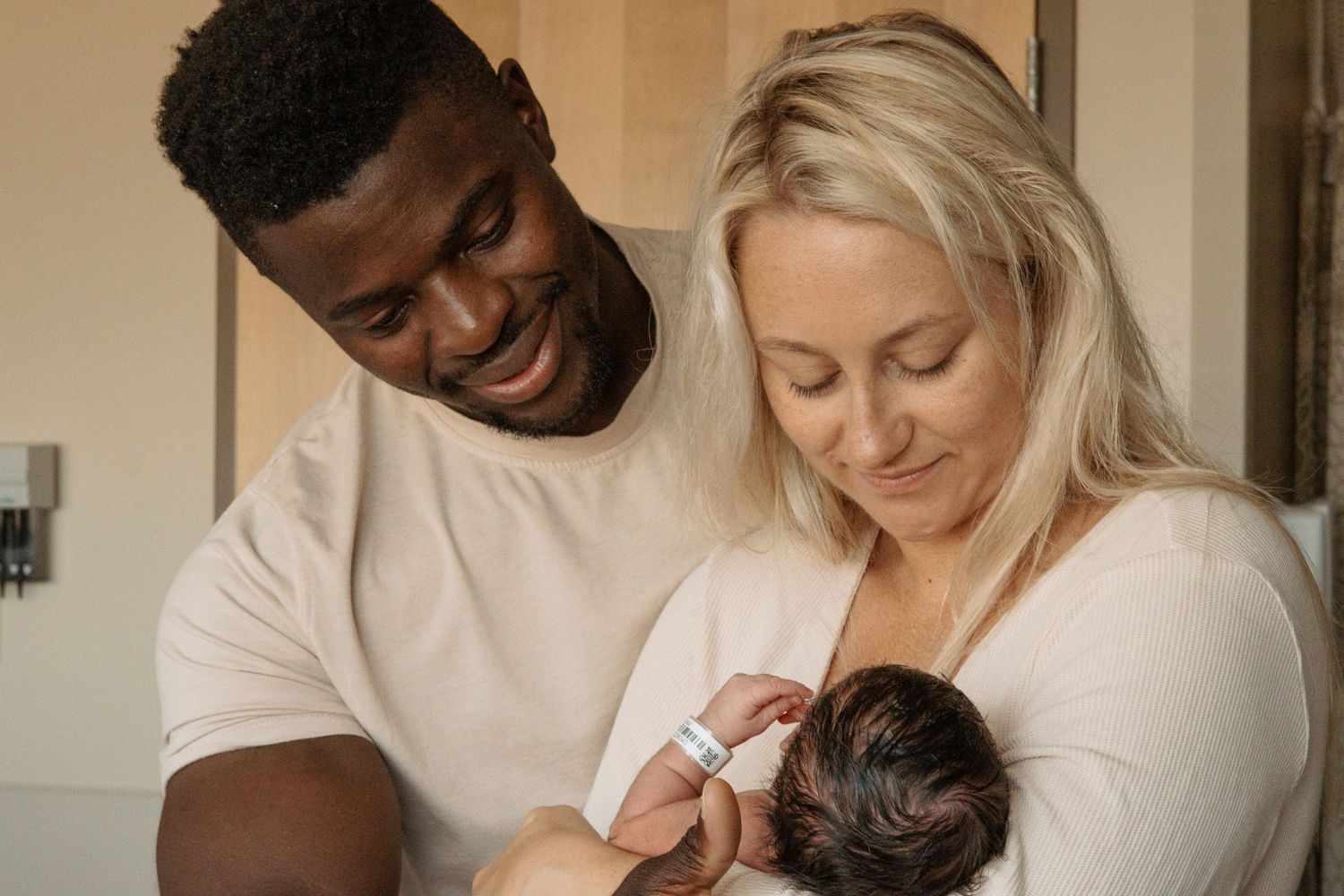 A tender family moment while feeding a newborn baby in a warmly lit room.
