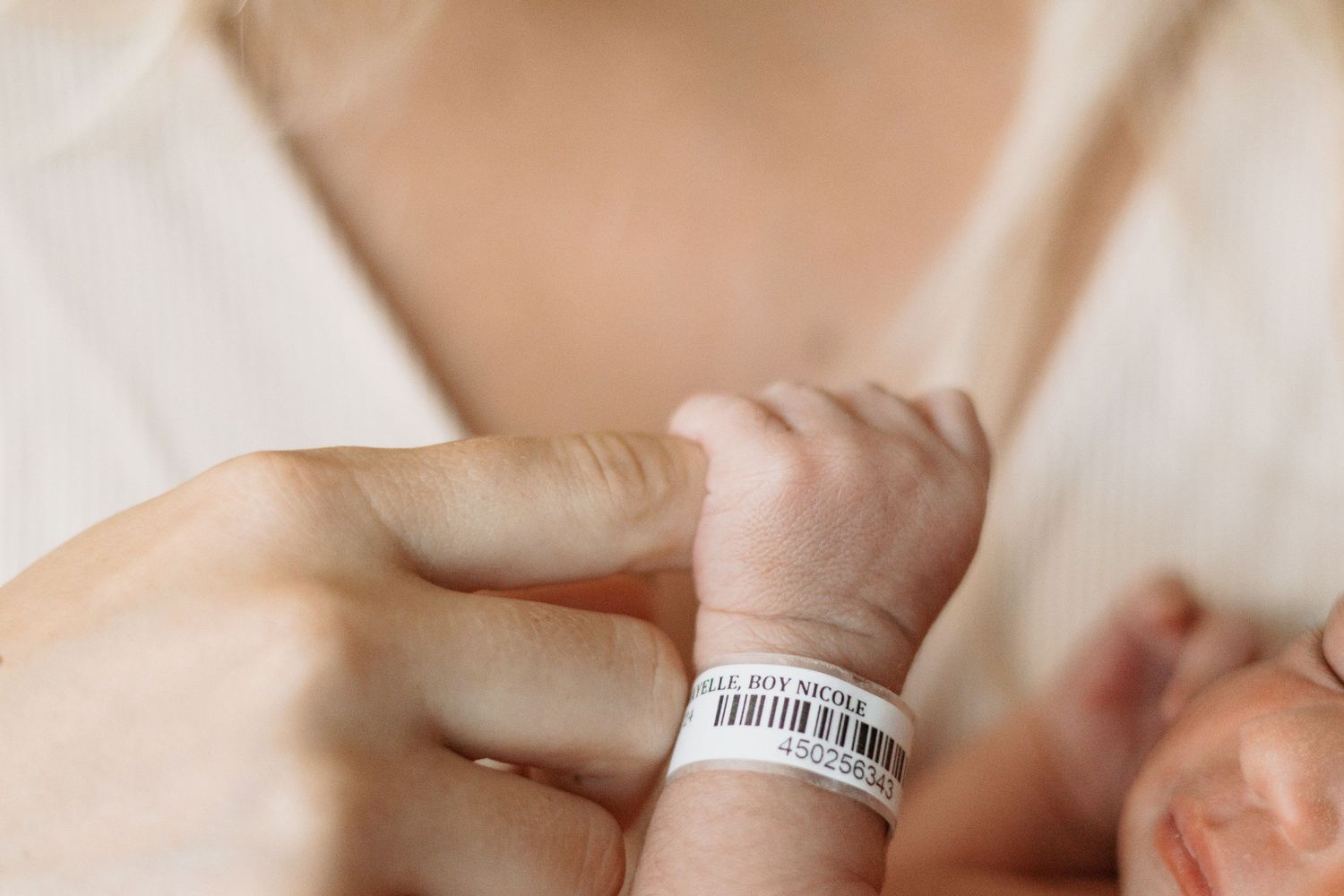 Close up of tiny newborn wrist with hospital identification bracelet.
