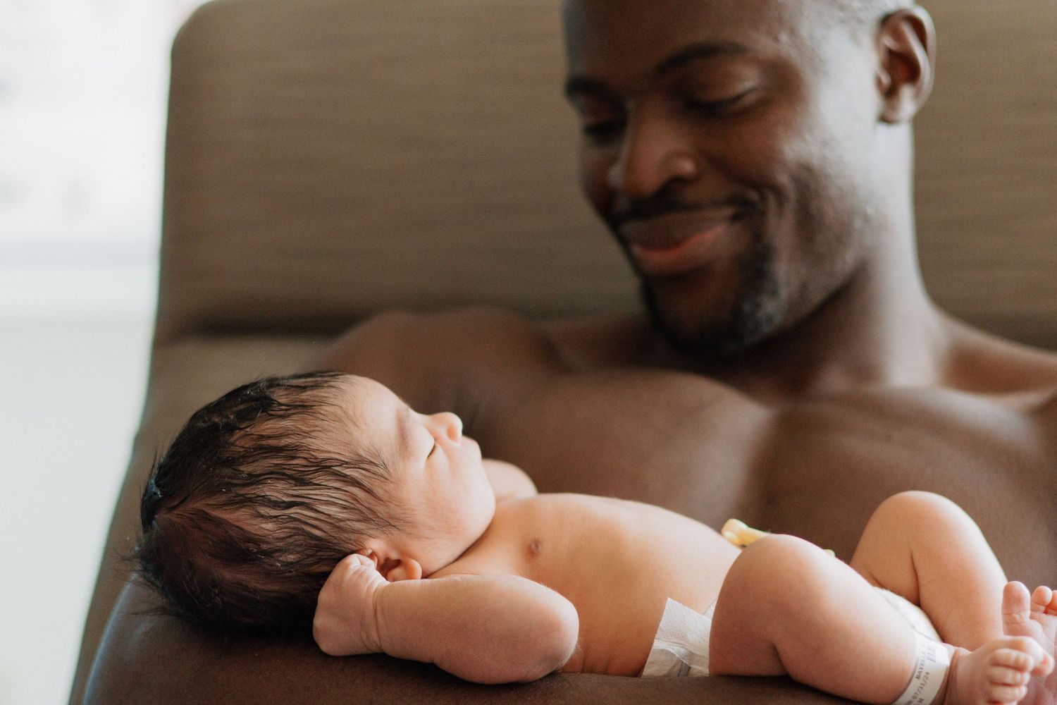 A sleeping newborn baby rests peacefully against a caregiver's chest in a tender moment.