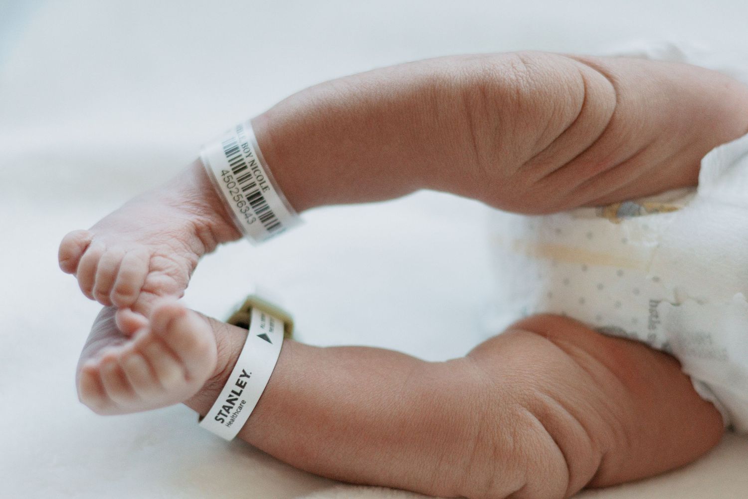 Close-up of a newborn baby's feet with hospital identification bands.