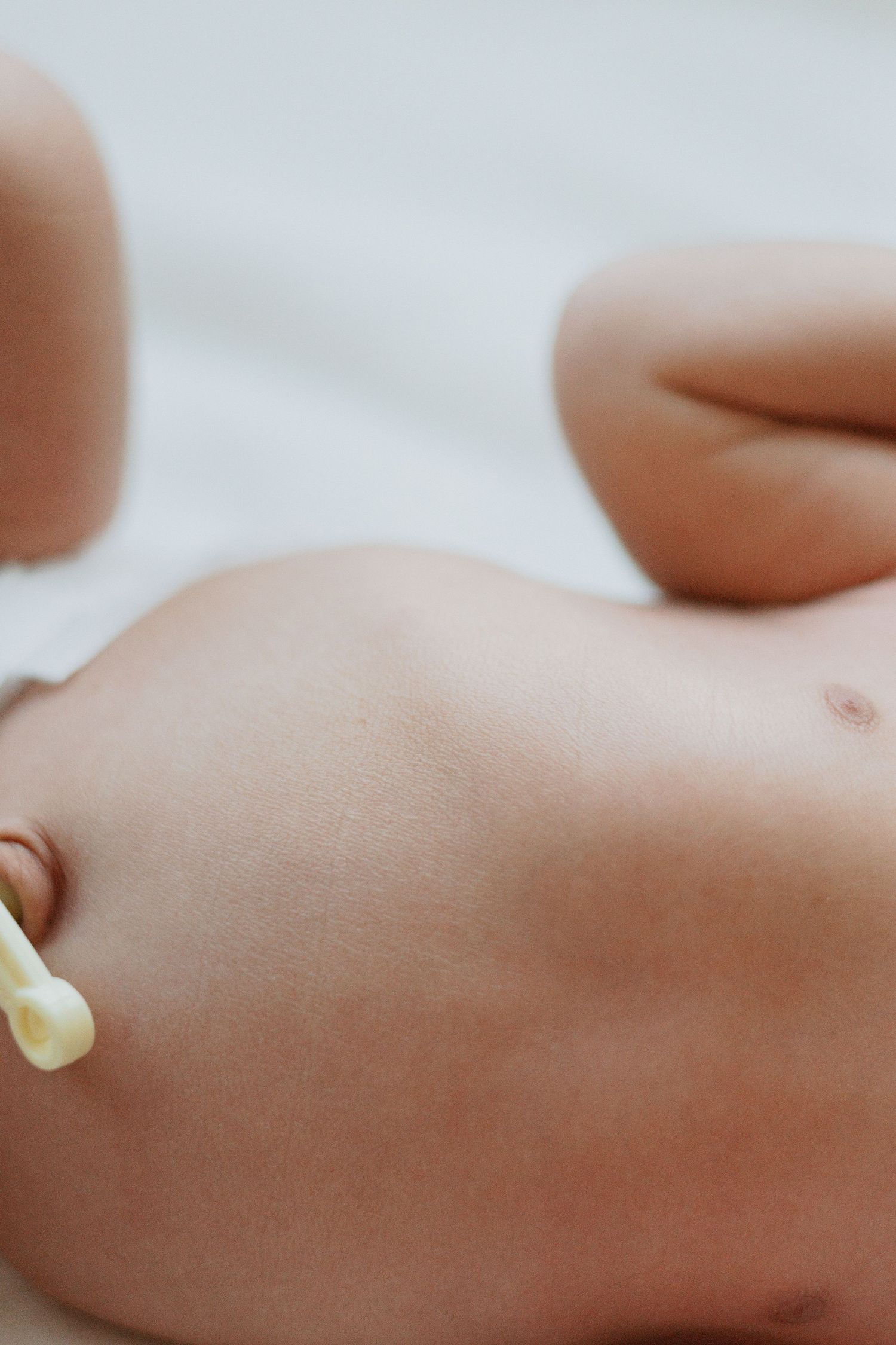 Close-up shot of a newborn baby's belly with umbilical cord clip visible.
