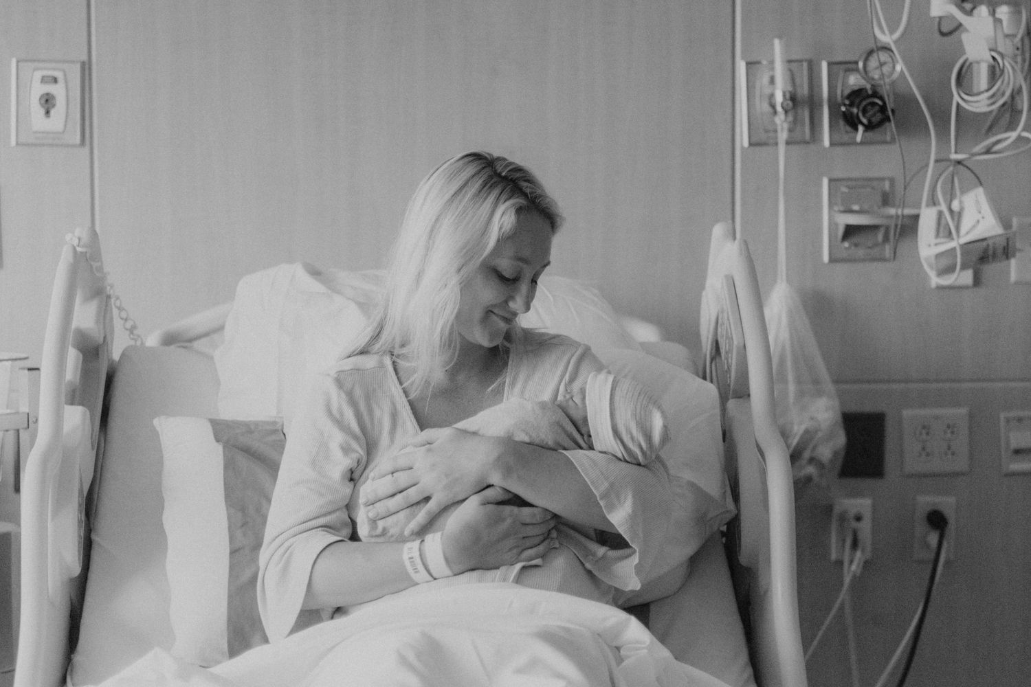 Black and white image of mother and newborn bonding in hospital room.