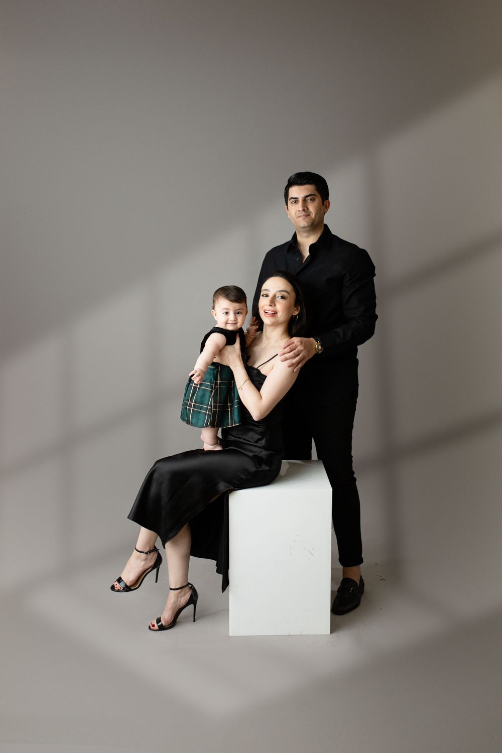Dramatic studio portrait with diagonal shadows and family in formal black attire.
