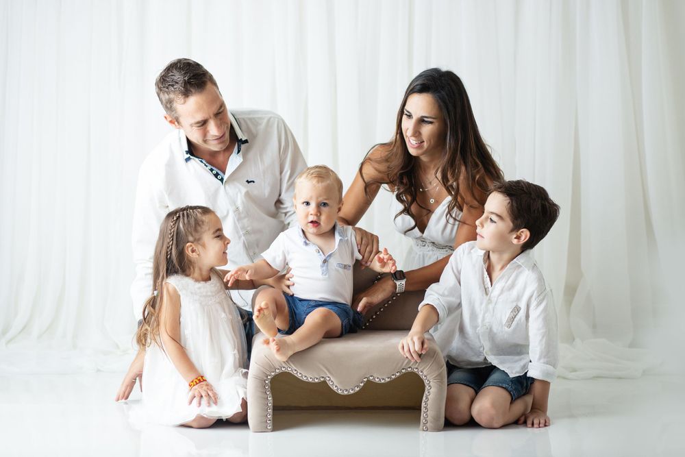 Family sitting together on couch in white outfits having fun and playing.