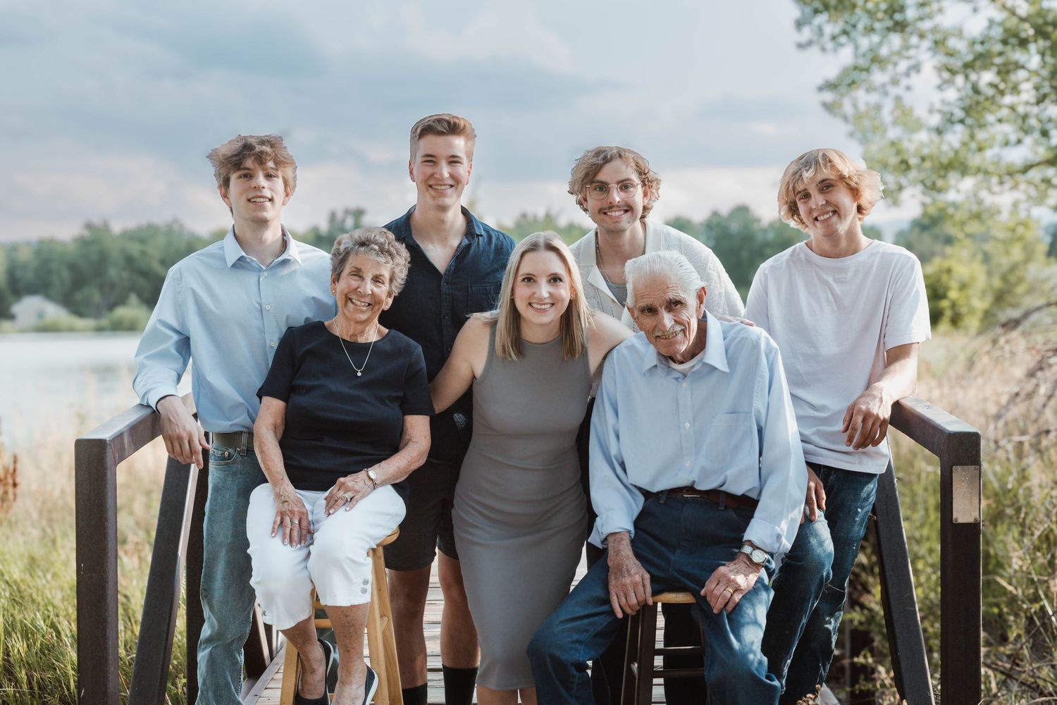 Multi-generational family group posing together on wooden deck with lake view.