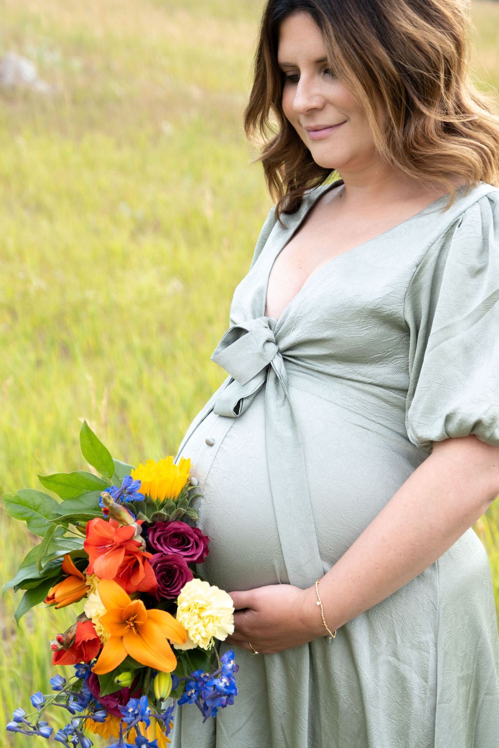 A sage green dress and colorful wildflower bouquet create a spring meadow portrait.