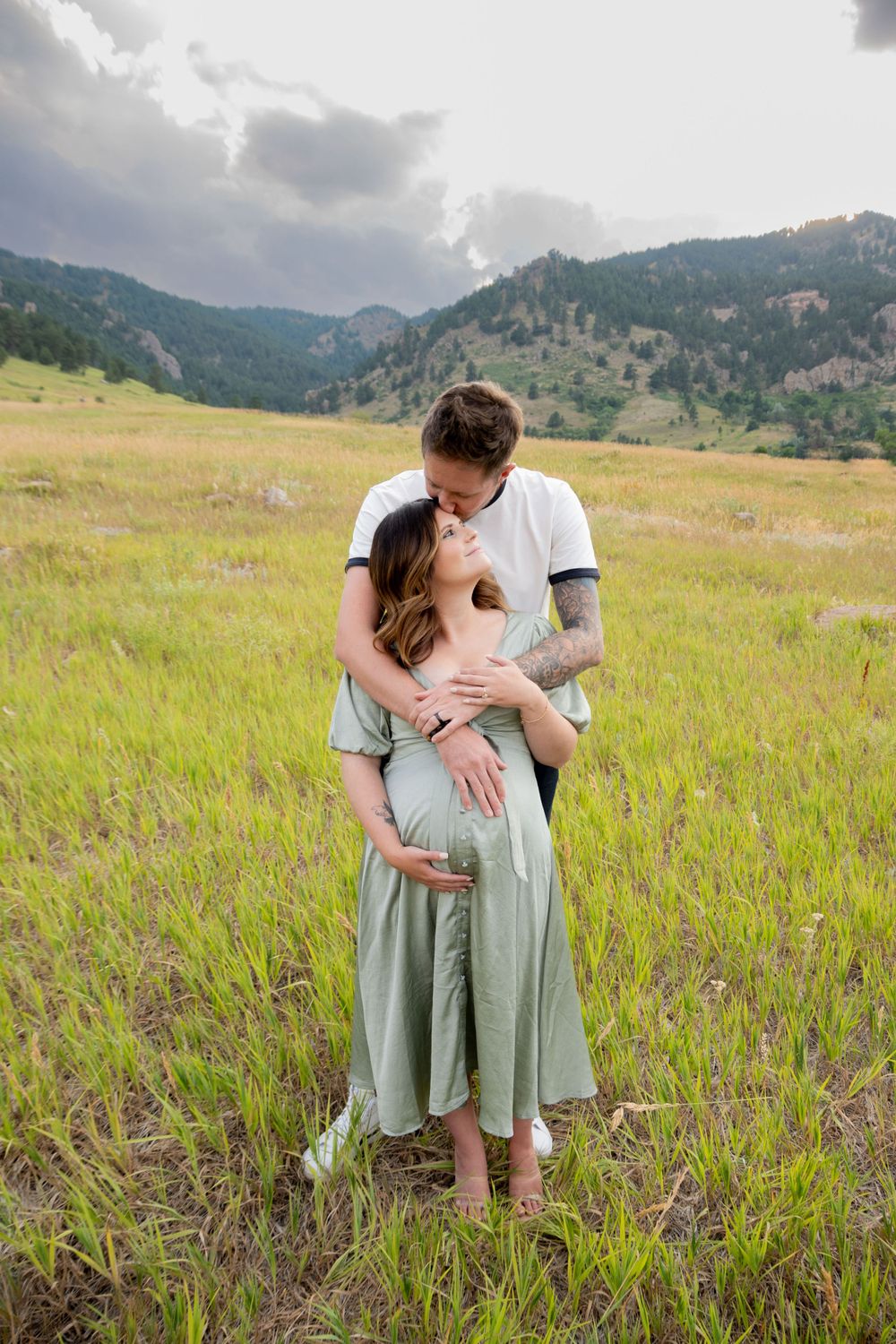 A couple shares romantic moments in a wildflower meadow with mountain vistas.