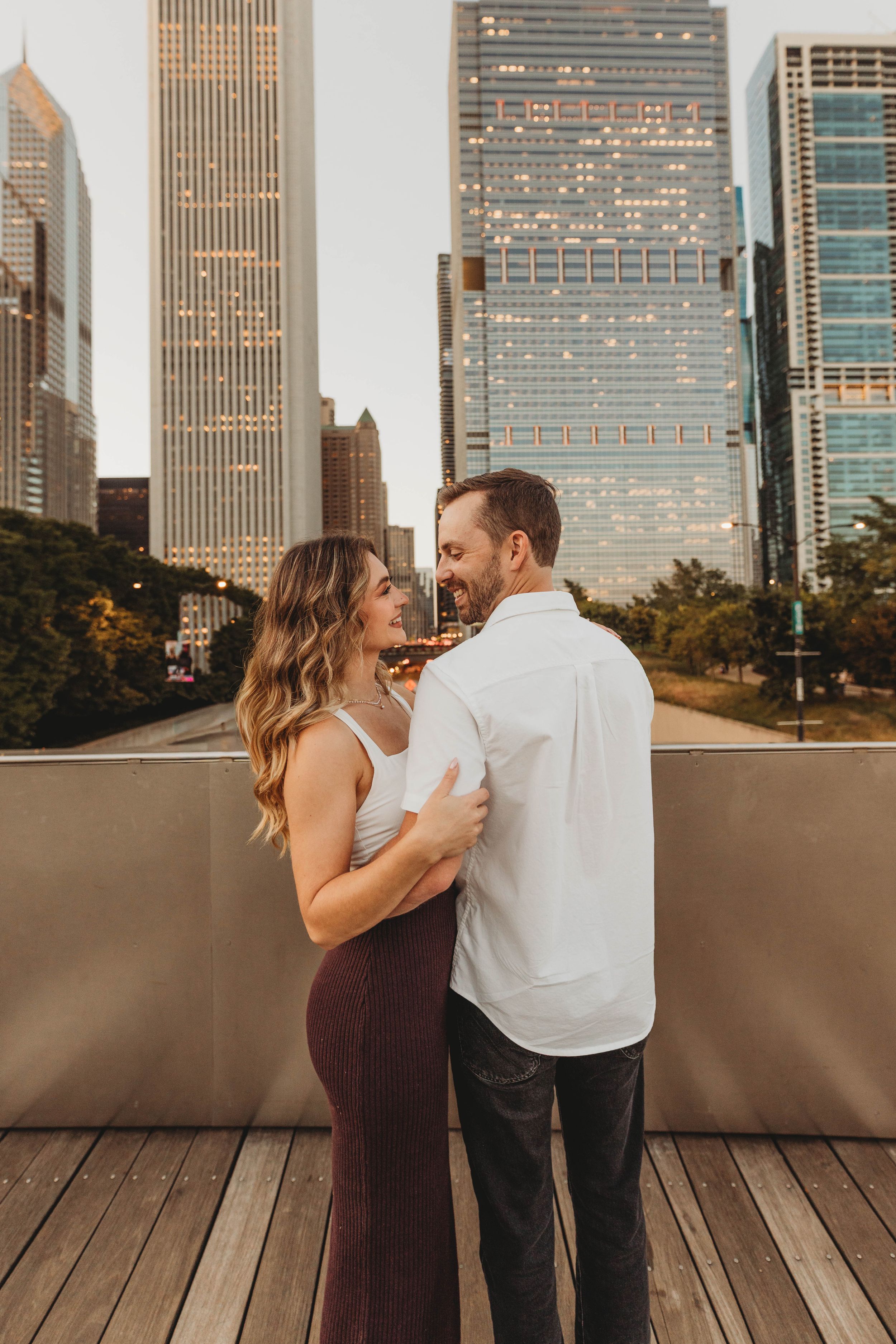 Romantic couple sharing an intimate moment against Chicago city skyline at sunset on urban rooftop deck.