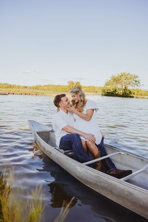 Couple sharing romantic moment in canoe on peaceful lake during sunset.
