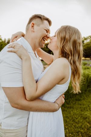 Intimate couple portrait with white outfits against bright natural background.