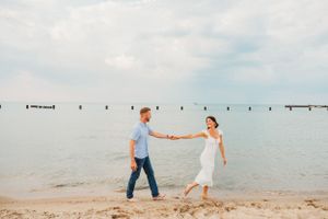 Beach engagement session with couple walking along Lake Michigan shoreline.