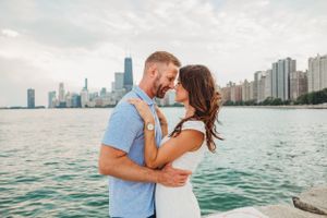 Romantic couple embraces against Chicago skyline backdrop at North Avenue Beach during sunset.