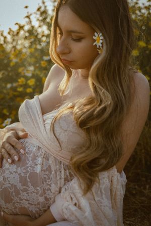 Dreamy portrait with white lace dress and flower in hair during sunset.