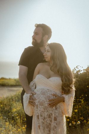 Couple embraces in golden sunlight among yellow wildflowers.