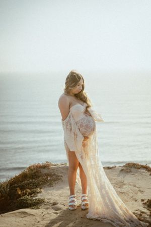 Ethereal beach portraits with flowing lace dress against soft ocean light.