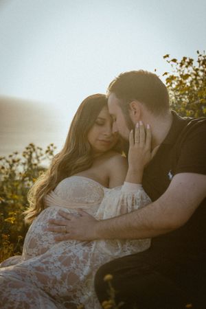 Intimate couple's portrait among wildflowers at sunset with soft natural lighting.