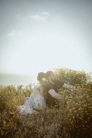 Romantic couple embracing in field of yellow flowers during golden hour.