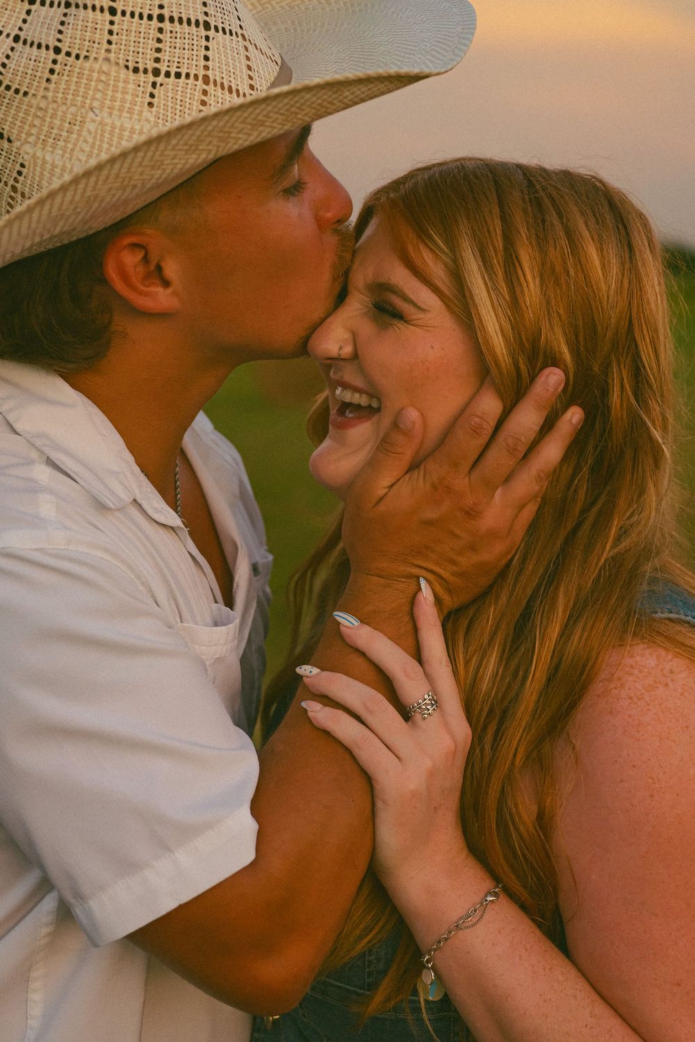 An intimate moment captured between a couple sharing a tender kiss outdoors.