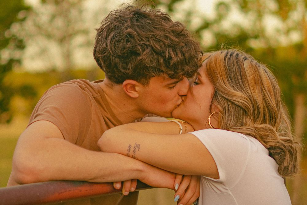 A tender moment between a couple sharing a kiss in warm golden sunlight.