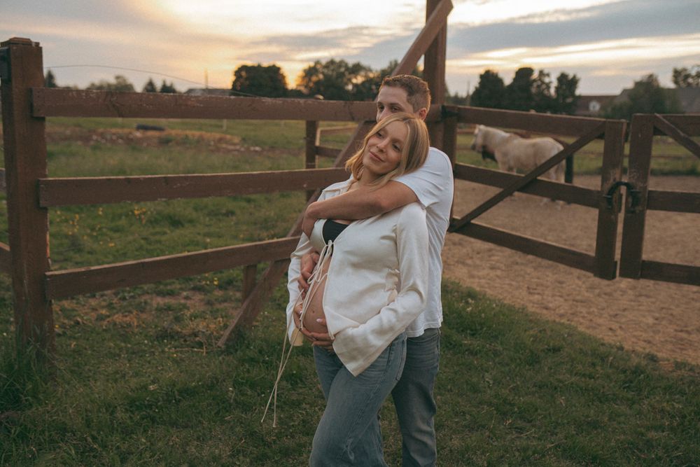 A joyful sunset portrait by a wooden fence in a rural setting.
