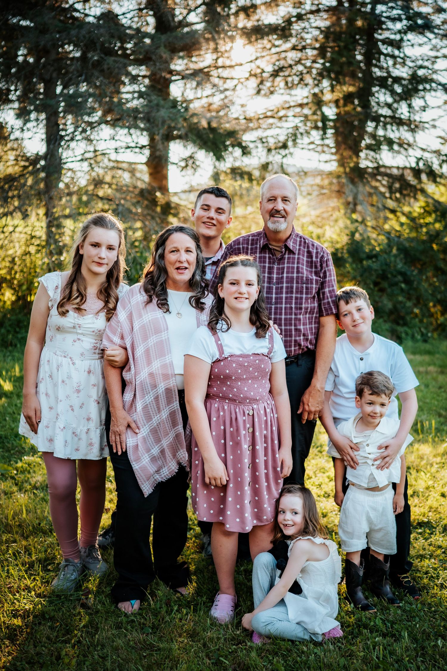 Family portrait session in field with dramatic cloudy sky at golden hour.