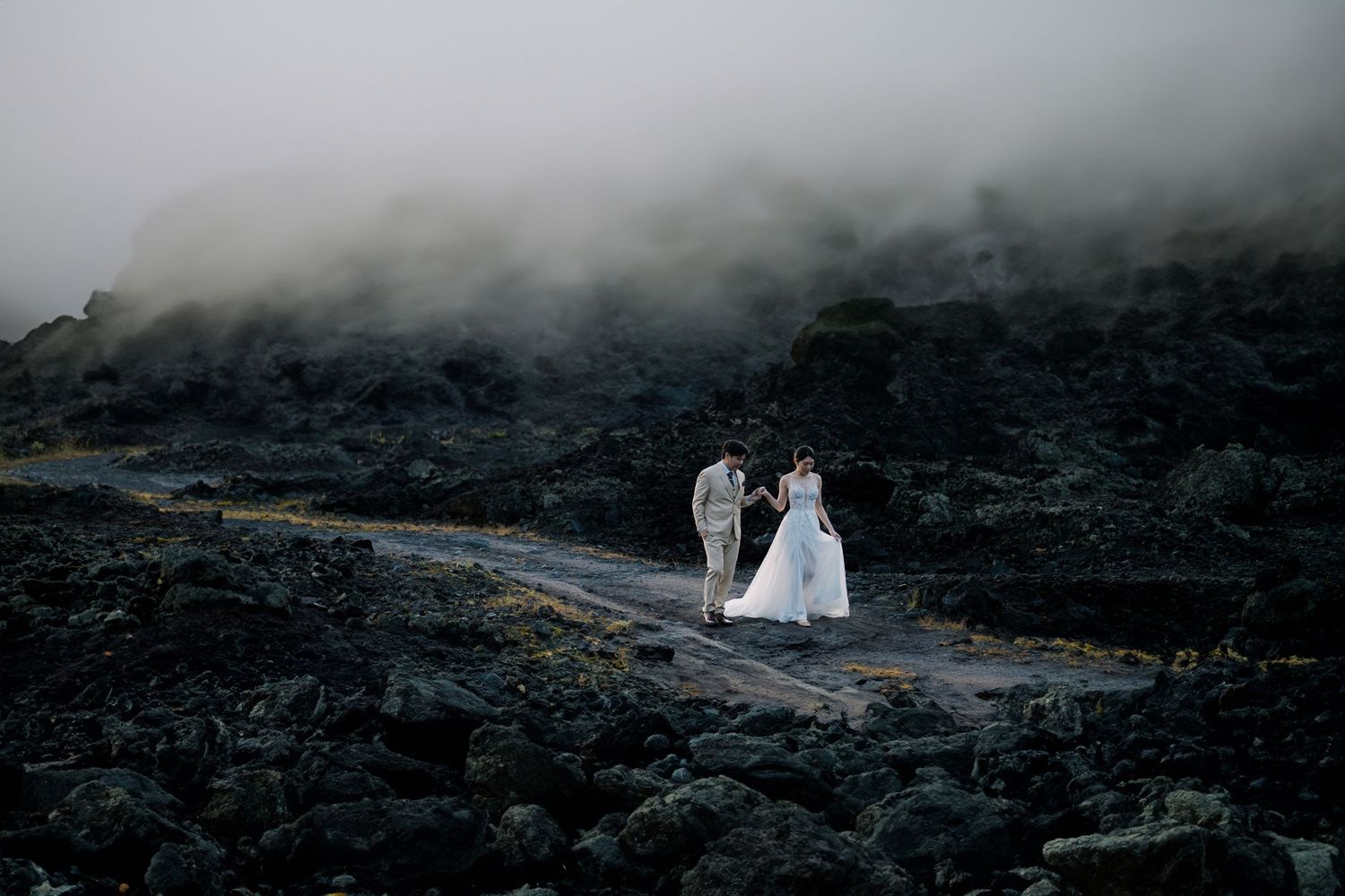 Dramatic wedding photos captured on foggy volcanic landscape with moody atmosphere.
