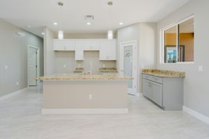 Modern kitchen layout with granite breakfast bar, white cabinets, and grey lower cabinets.