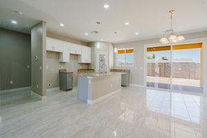 Sleek kitchen space with white and grey cabinetry, granite counters, and large sliding doors.