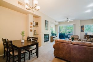 Open concept dining and living space with dark wood table, leather sofa, and modern light fixture.